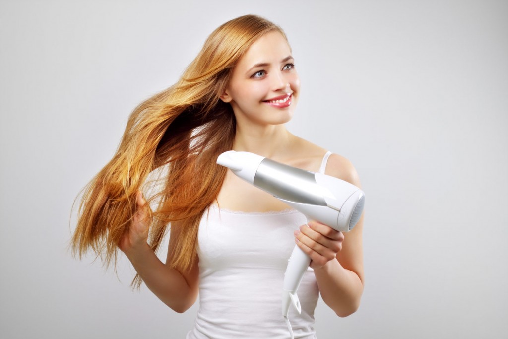 Blonde girl using a hair dryer on her hair